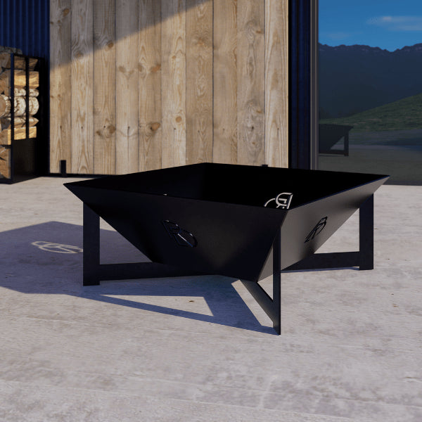 Basin firepit with black metal frame on concrete surface, wooden wall, and mountain view in the background