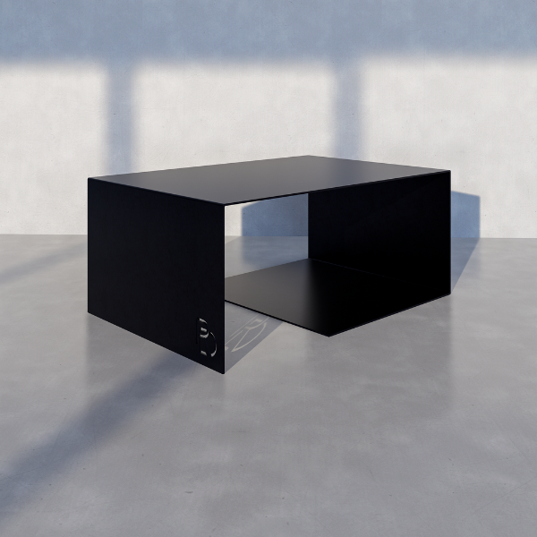 Cascade Coffee Table — Black cube-shaped table on a gray floor with a light blue wall background.