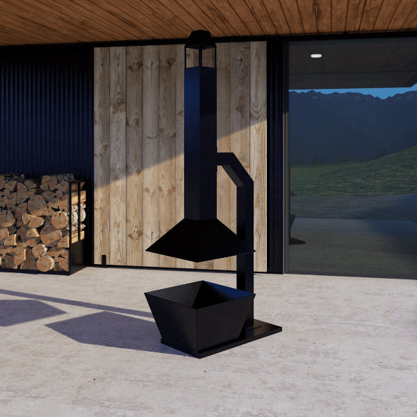 Black outdoor stove or fireplace in front of a wooden building with mountains in the background