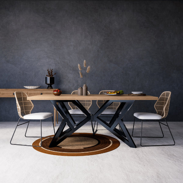 Dining table with black metal legs and chairs against a dark wall.
