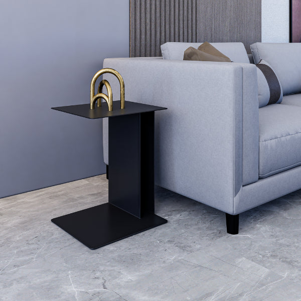 Wyatt black side table with gold decorative item next to a gray sofa in a modern living room